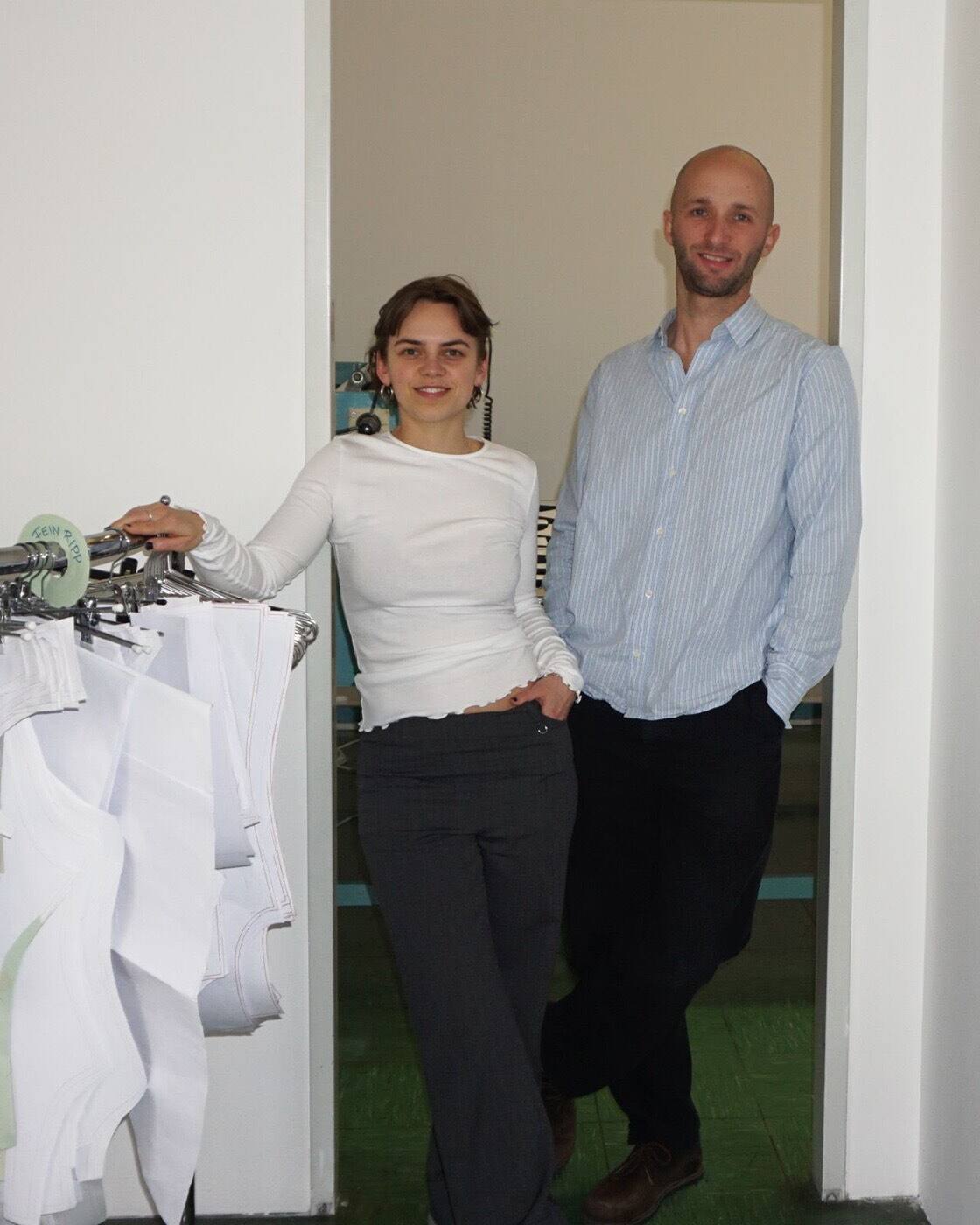 The founding team of Soda Lingerie next to a rack of patterns in the studio